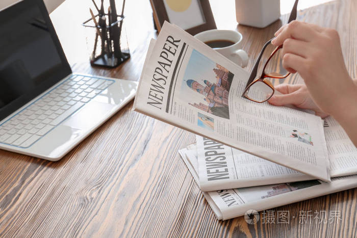 在桌上看报纸的年轻妇女