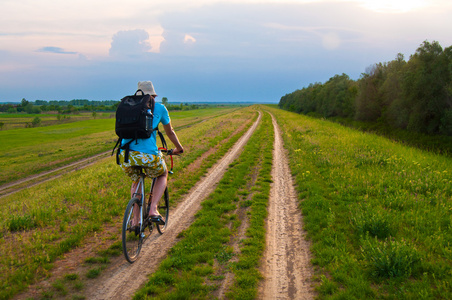 年轻的旅行者在乡村道路上骑自行车照片
