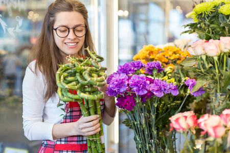 花商, 年轻女子站在店里, 手里拿着鲜花高兴地看着相机