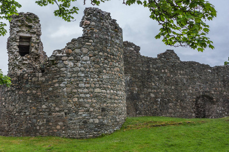 Torlundy, 苏格兰2012年6月11日 Comyn 角塔在灰褐色自然石头防御墙壁 Invelochy 城堡。在绿树和