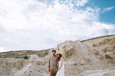 情侣牵手站在沙峡谷与 cludy 的天空