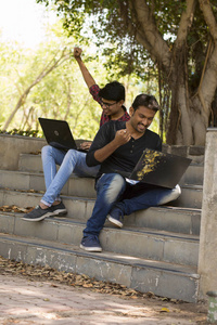两位快乐的年轻学生在公园里工作笔记本电脑