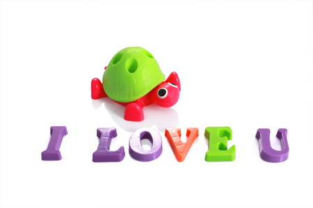 玩具龟与文字我爱你由孤立的塑料字母写在惠特