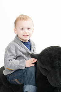 微笑的男孩坐在黑色大长毛绒在白色背景下