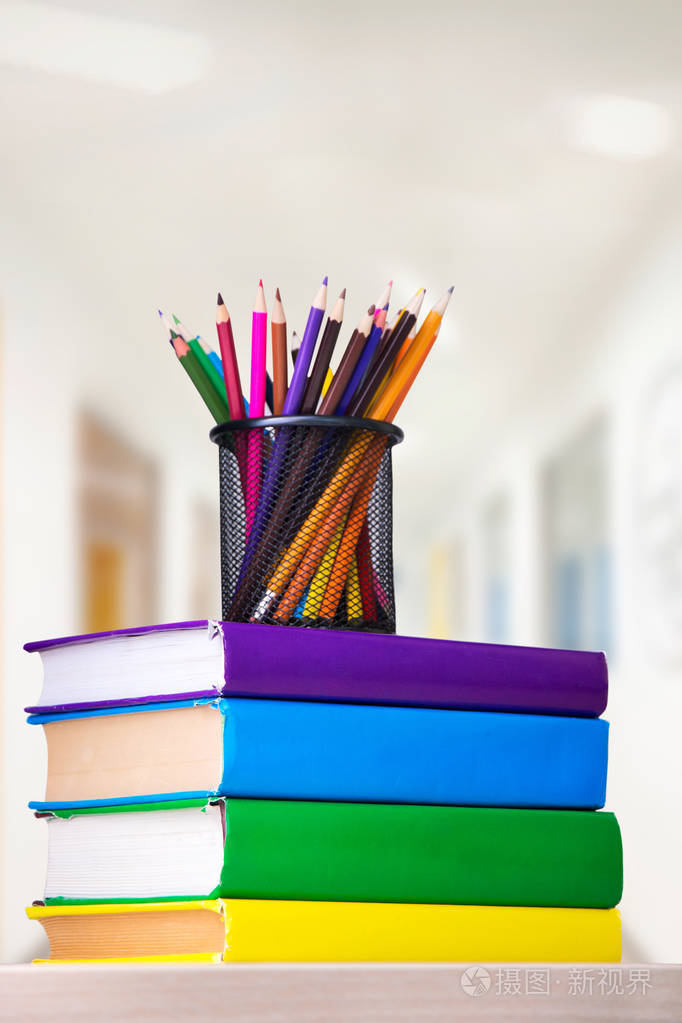 用彩色铅笔在桌子上的一摞书上的玻璃, 学校概念