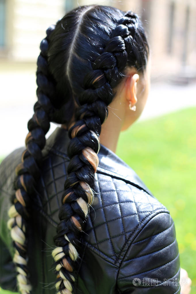 两条辫子一个时髦的女孩的发型由主理发师编织工作的结果与自然背景的