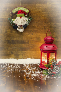 圣诞装饰的木质背景。红色圣诞蜡烛灯笼和绿色松树星, 装饰着雪