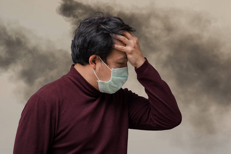 云烟缭绕亚洲男子戴口罩反对空气污染, 咳嗽在烟雾缭绕的烟囱工厂与云