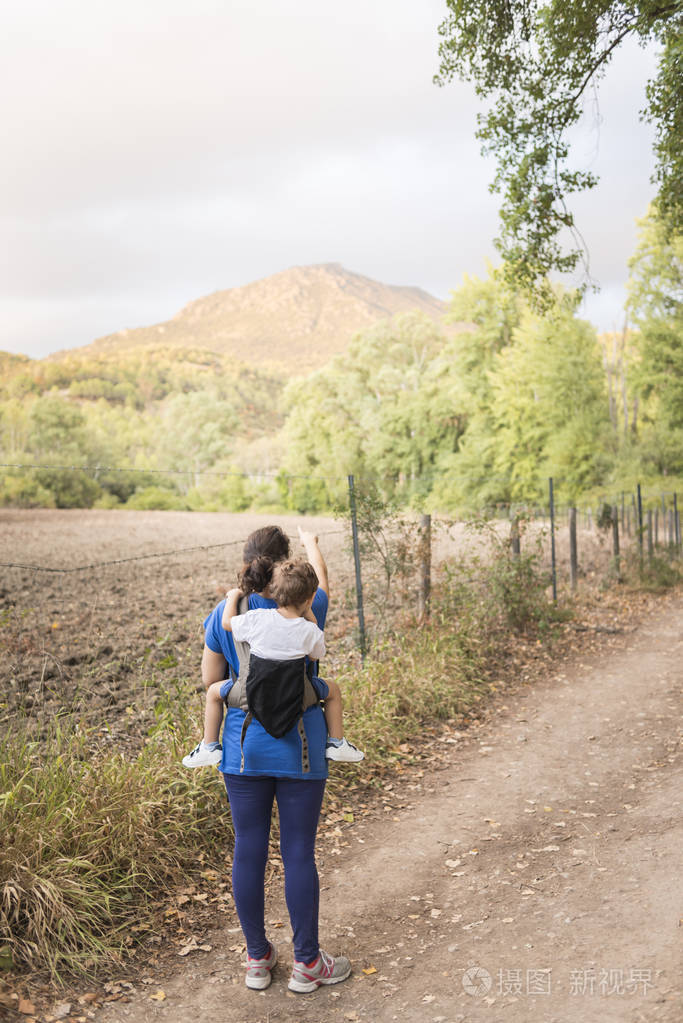 母亲与她的儿子在她的背部徒步旅行的彩色照片