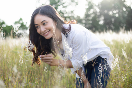 亚洲妇女愉快的微笑在放松的时间在草甸和草