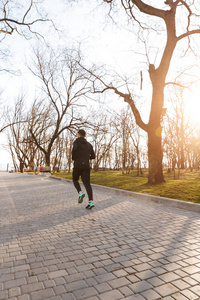 健康青年运动员在户外耳机慢跑的肖像