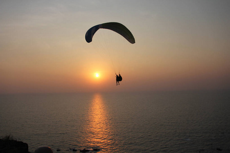 在海的背景下的滑翔伞, 日落或黎明。美丽的海景。极限运动。滑翔伞飞过海面。印度果阿