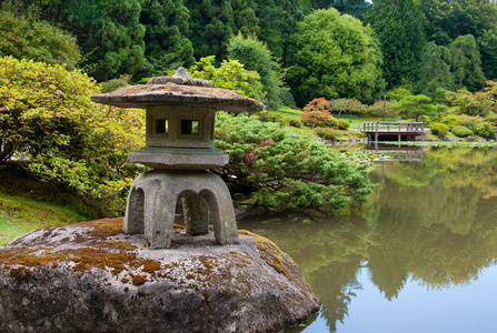 日本花园在池塘上的古代灯笼