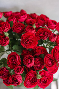 在木桌上的美丽的花朵鲜艳的红色花束。植物概念。春天的颜色。花店里花匠的工作。垂直照片
