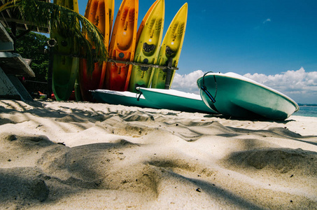 在阳光明媚的日子, 热带荒芜的白色沙滩上五颜六色的皮划艇。蓝天和清澈的海水背景