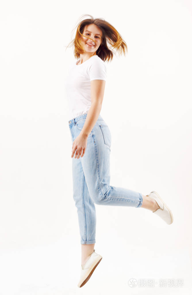 快乐女孩的t恤衫和牛仔裤跳跃在白色演播室全身