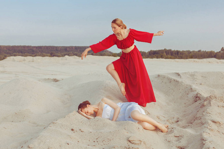 年轻女子躺在沙滩上, 另一个穿红衣服的女人, 使她身旁的舞步