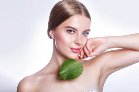美丽的女人脸上的肖像与绿叶的概念皮肤护理或有机化妆品。工作室肖像