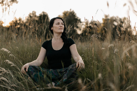 一个女人坐在高高的草丛中, 看着远处的画像。享受大自然的女人