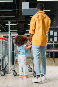 美国黑人男子站在超市购物车附近的非洲裔美国人的后视图