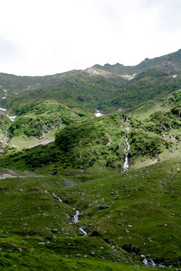 Transfagarasan 在罗马尼亚的绿草和石头中有瀑布的山河