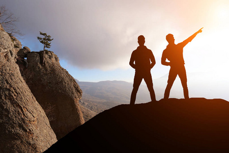 两名男子站在一块岩石望著远方的剪影摄影图