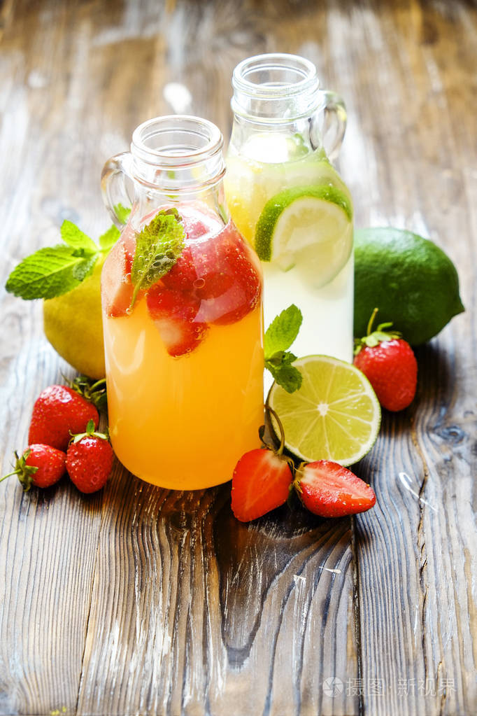 三瓶新鲜冰冷的柠檬水, 不同口味的饮料有柠檬, 橙, 柚子, 石灰, 薄荷叶和草莓 grunged 木桌背景。顶部视图, 复制空