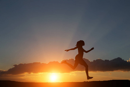 一个女孩在美丽的夕阳与海岗右边跑的剪影