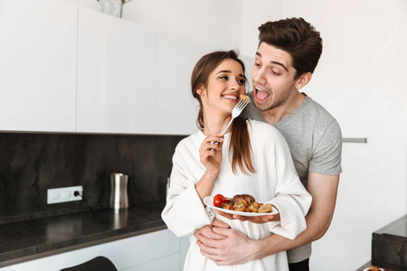 一个漂亮的年轻夫妇的肖像举行餐盘与食物, 而站在厨房