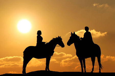 两个人的剪影在马背背景美丽的日落
