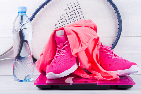 粉红色运动鞋和 t恤, 健身, 电子秤, 一瓶水, 灰色背景和网球拍