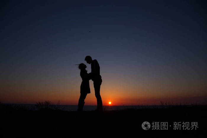 剪影男孩和女孩在一个美丽的黄昏,手牵着手