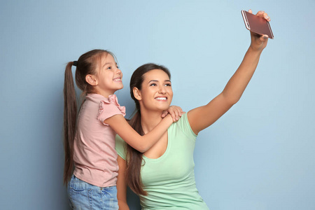 年轻的母亲与小女儿采取自拍在颜色背景