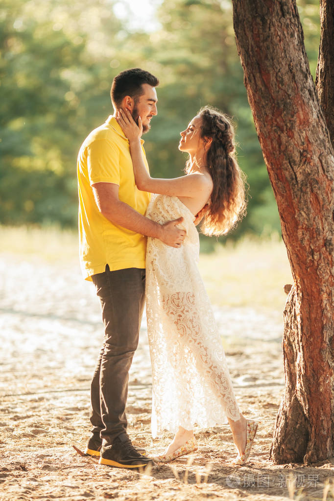 年轻迷恋夫妇拥抱在森林反对树的背景