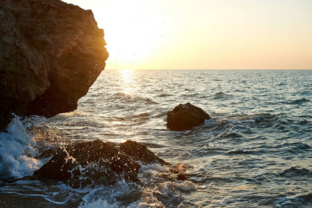 日落在海边。金砂。海浪在沙滩和岩石上翻滚