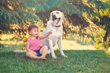 可爱可爱的小白种欧洲婴儿女孩坐在公园外面的狗的肖像。儿童玩坐在动物家养宠物。快乐童年概念
