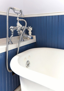 古色古香的硬件和蓝色木墙的白色浴缸