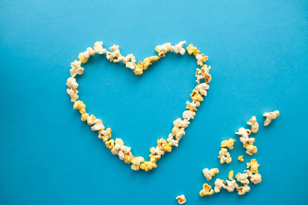 食品。从爆米花的心脏形态的图像。蓝色背景的美味爆米花。电影院