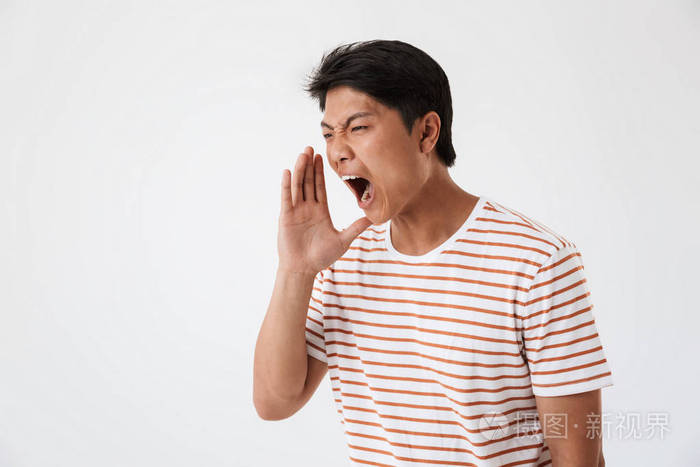 关闭了一个年轻的亚洲男子的肖像大声呼喊与手臂在他的脸上孤立的白色