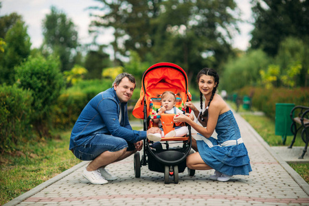 爸爸妈妈和一个婴儿在 pakr 的婴儿车里散步