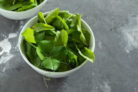 新鲜的绿色混合沙拉在一个碗在一个黑色的桌子上。健康理念