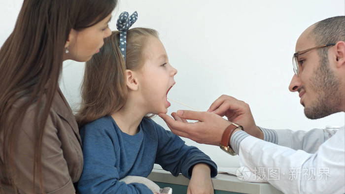 小女孩有喉咙检查用压舌板由一位男医生