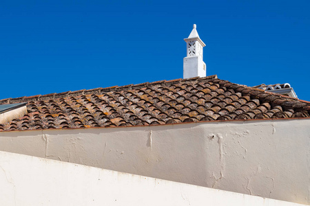 房子的白色墙壁线。屋顶与旧的传统瓷砖。华丽的白色典型的烟囱。明亮晴朗的蓝天。卡斯特罗马林堡, 阿尔加维, 葡萄牙