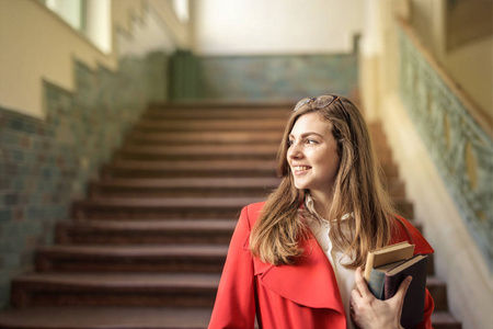 年轻女学生与她的书在大学的走廊微笑明亮