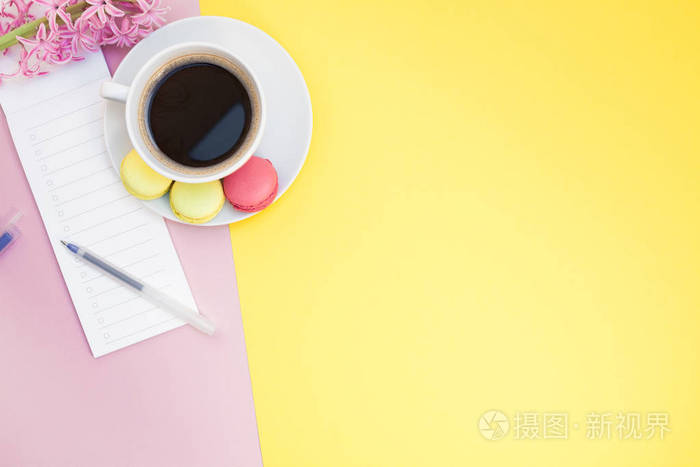 创意平躺照片的咖啡杯与杏仁和一个记事本与复制空间的粉红色和黄色背景最小的风格