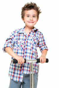 淘气的毛小男孩穿着短裤和衬衫和踏板车