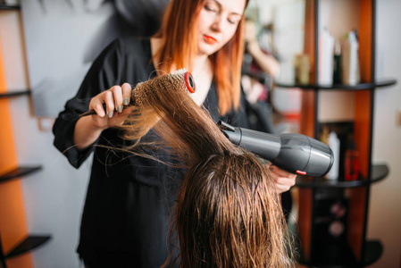 理发师烘干头发与烘干机, 女性 hairdress 在美发沙龙。美容工作室的发型制作