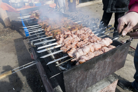 肉在烤肉串煎在露天烧烤, 在烧烤和厨师的手的可见烟雾