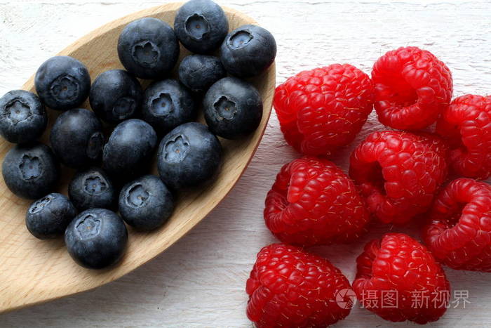 树莓和蓝莓在白板上木制厨房铲, 顶部视图, 关闭