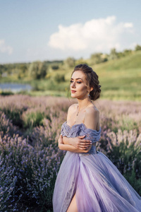 长紫色礼服的美丽的年轻妇女的画像站在薰衣草领域的姿势